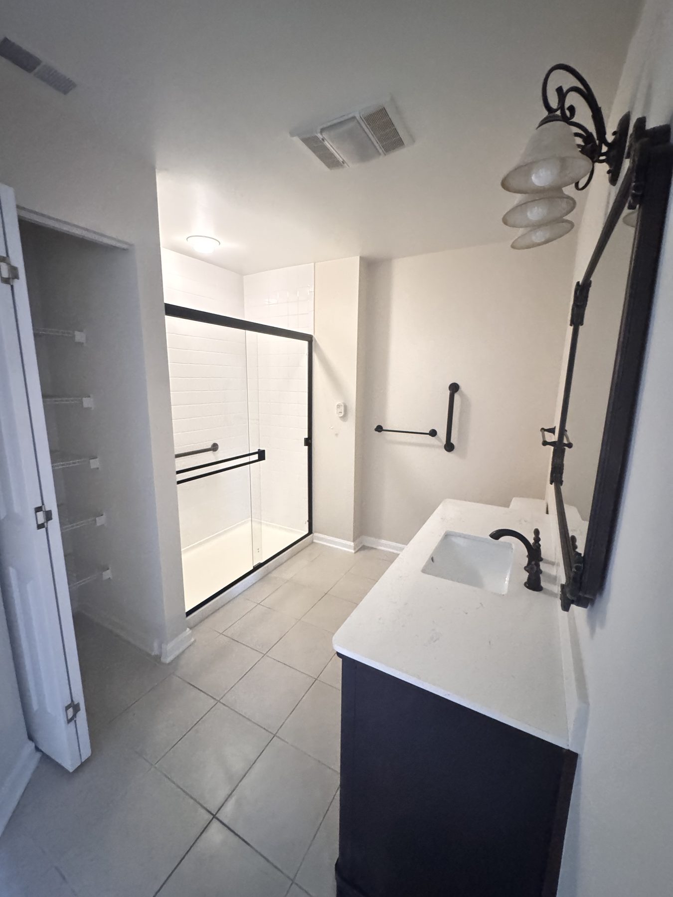 Renovated bath with a walk-in glass shower, tile flooring and accessible grab bars