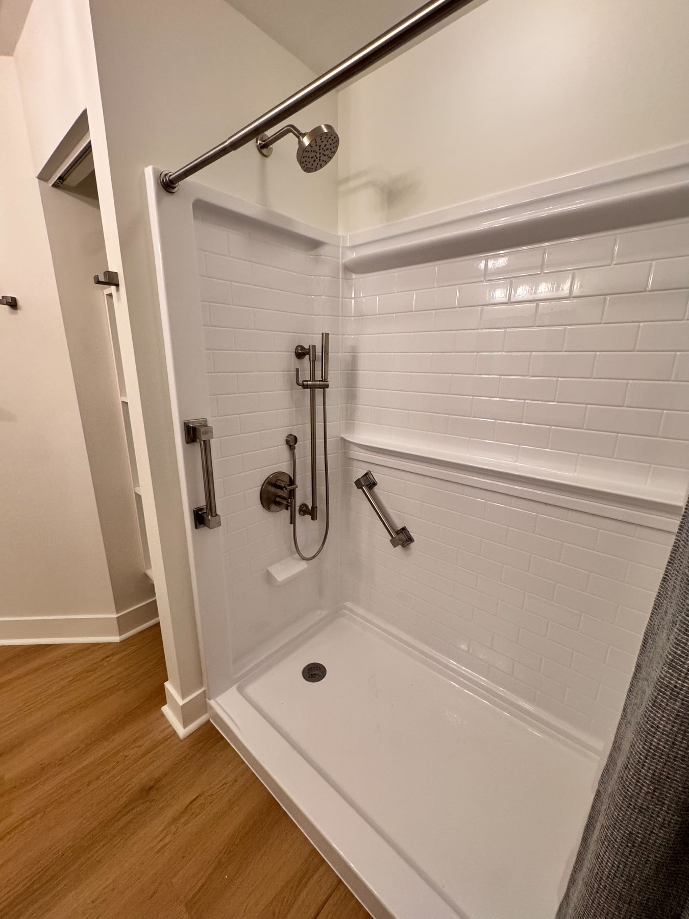 Tiled shower with a low-threshold pan, recessed niche and grab bars for accessible use