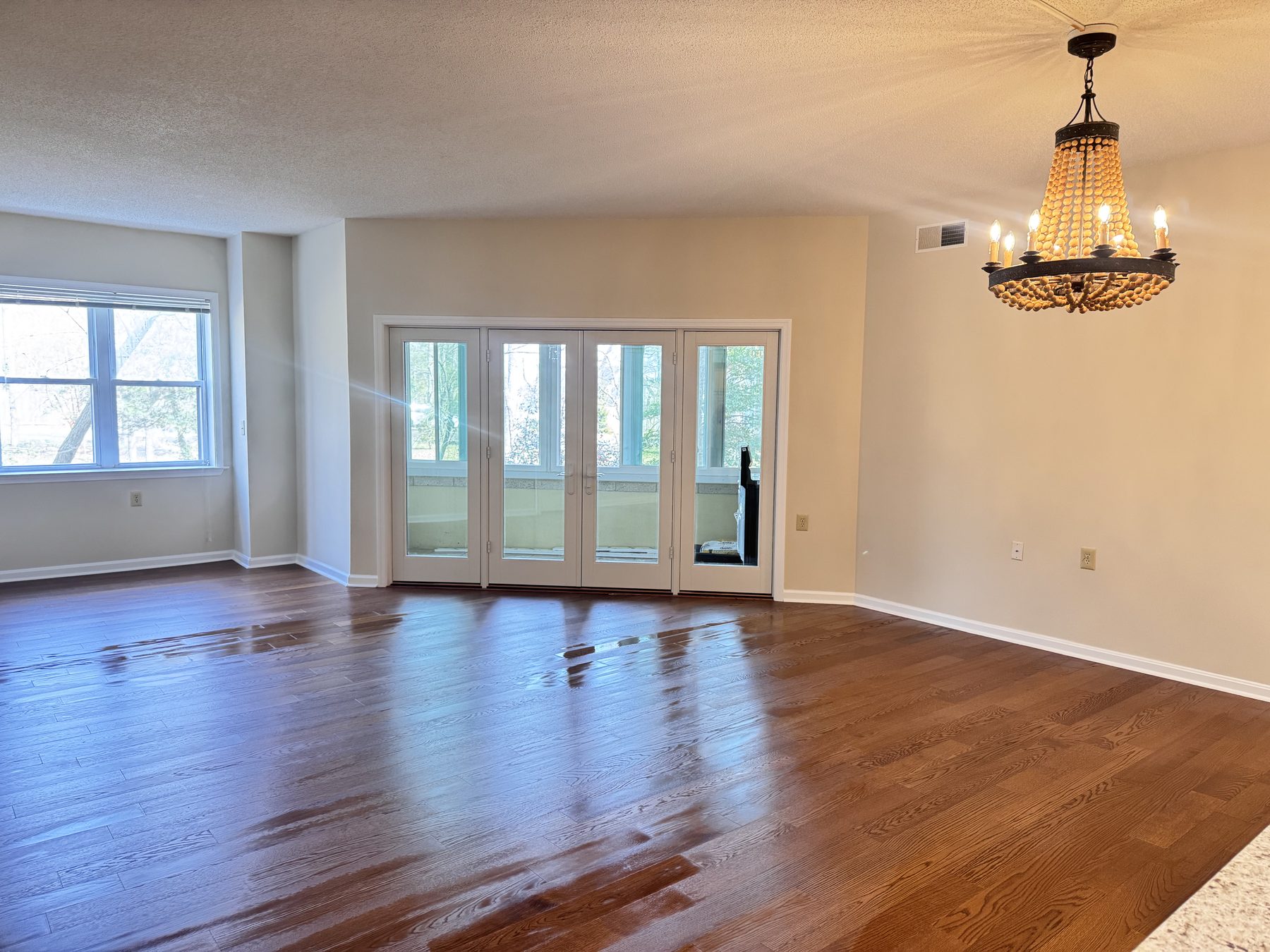 Living room in a renovated condominium with refinished red oak floors, opening to a rear balcony