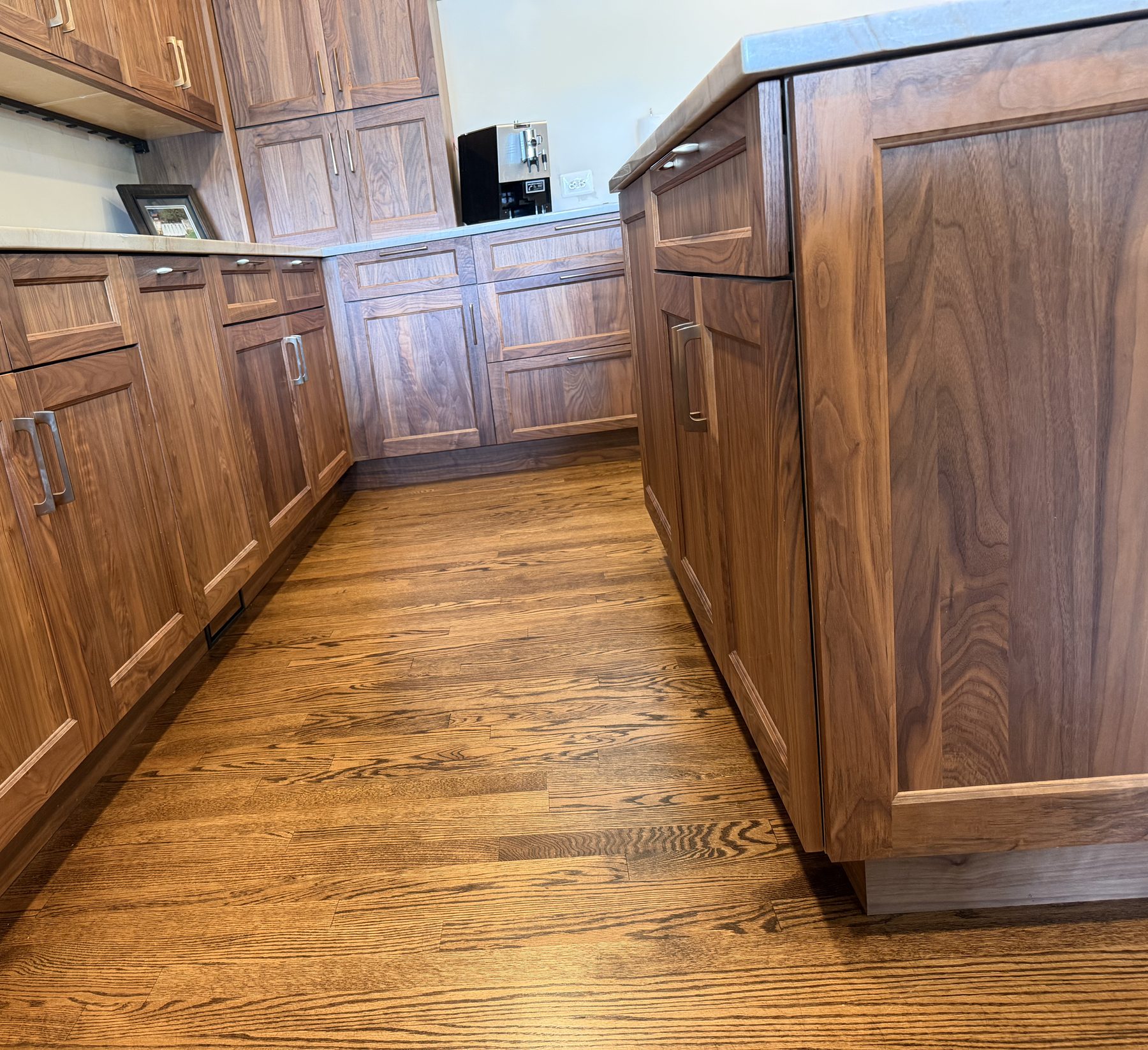 Flat-panel walnut base cabinetry and island over refinished red oak flooring