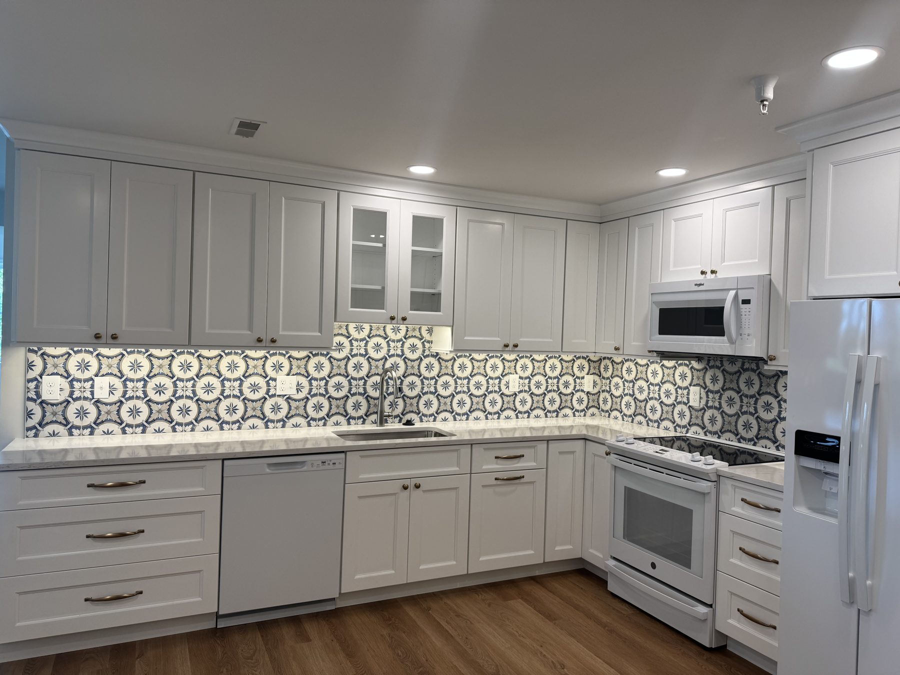 White shaker kitchen with a patterned encaustic-look tile backsplash and quartz counters